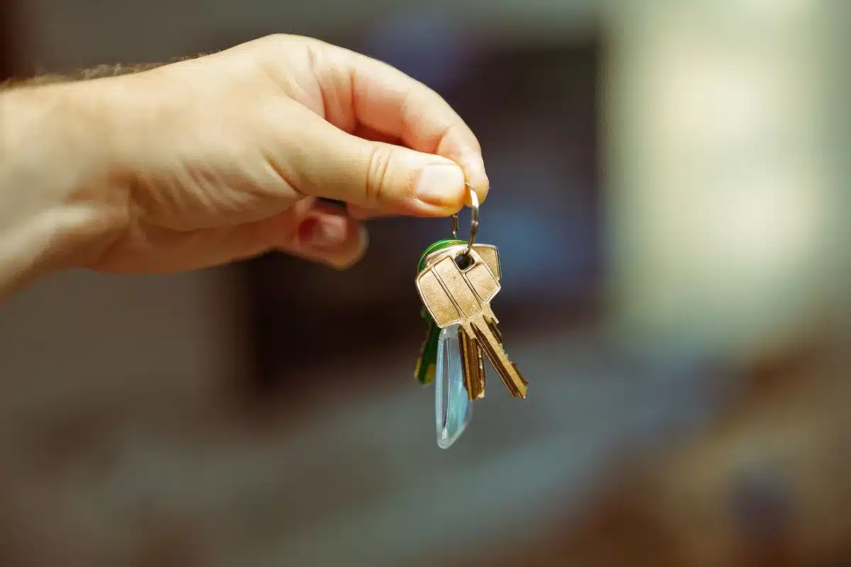 Deux personnes serrent la main à côté de documents de location et de clés d'appartement sur un bureau