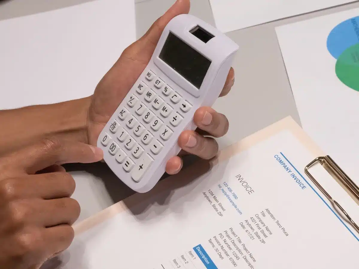 Mains examinant un contrat de bail et un budget sur un bureau avec calculatrice et stylo