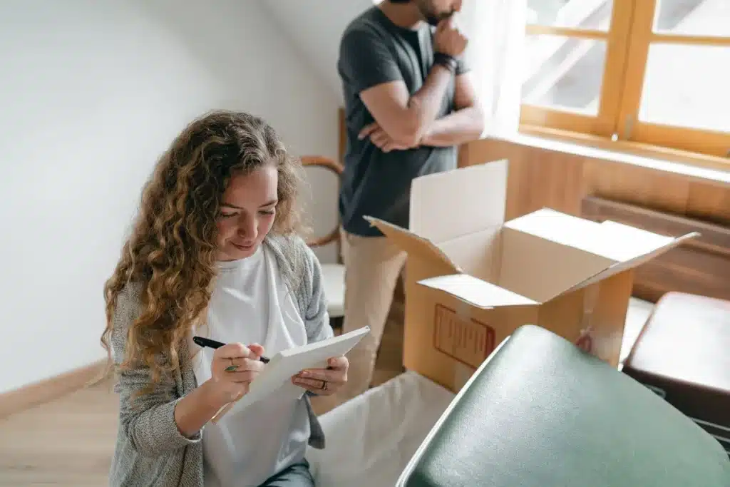 Mains tenant un document d'inspection et une liste de contrôle dans un salon lumineux avec appareils électroménagers vis