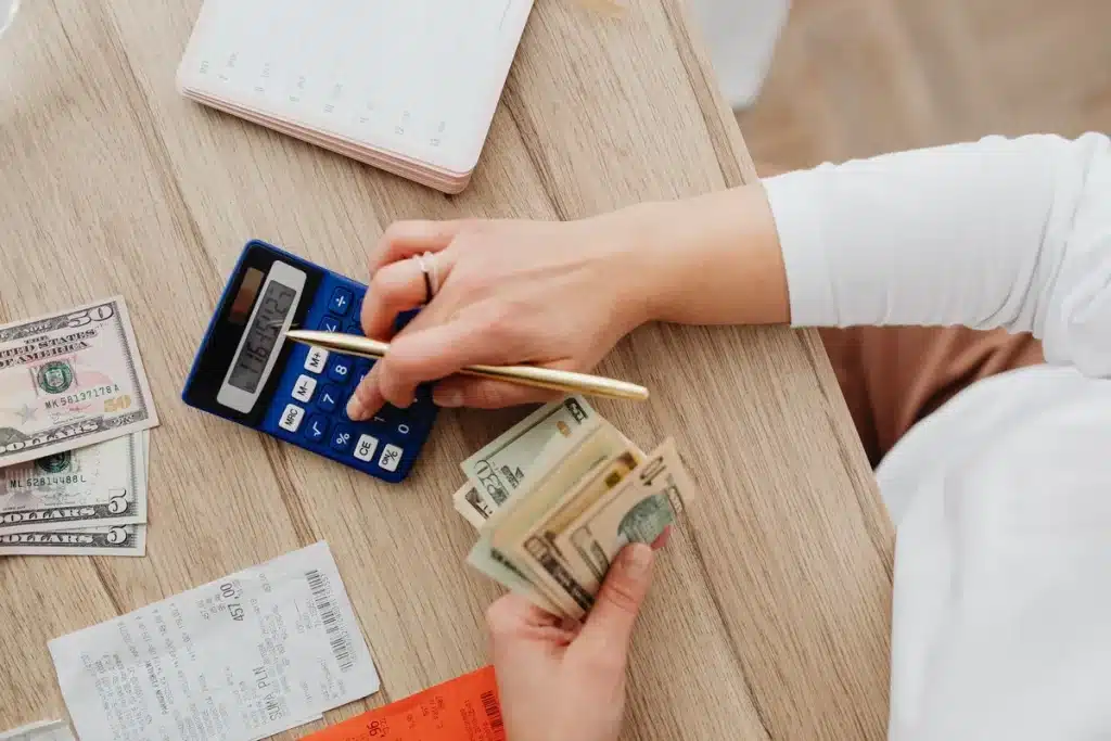 Mains tenant des documents financiers et un carnet d'épargne à côté d'une calculatrice sur un bureau