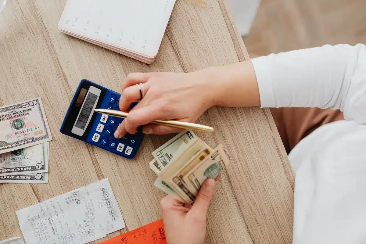 Mains tenant des documents financiers et un carnet d'épargne à côté d'une calculatrice sur un bureau
