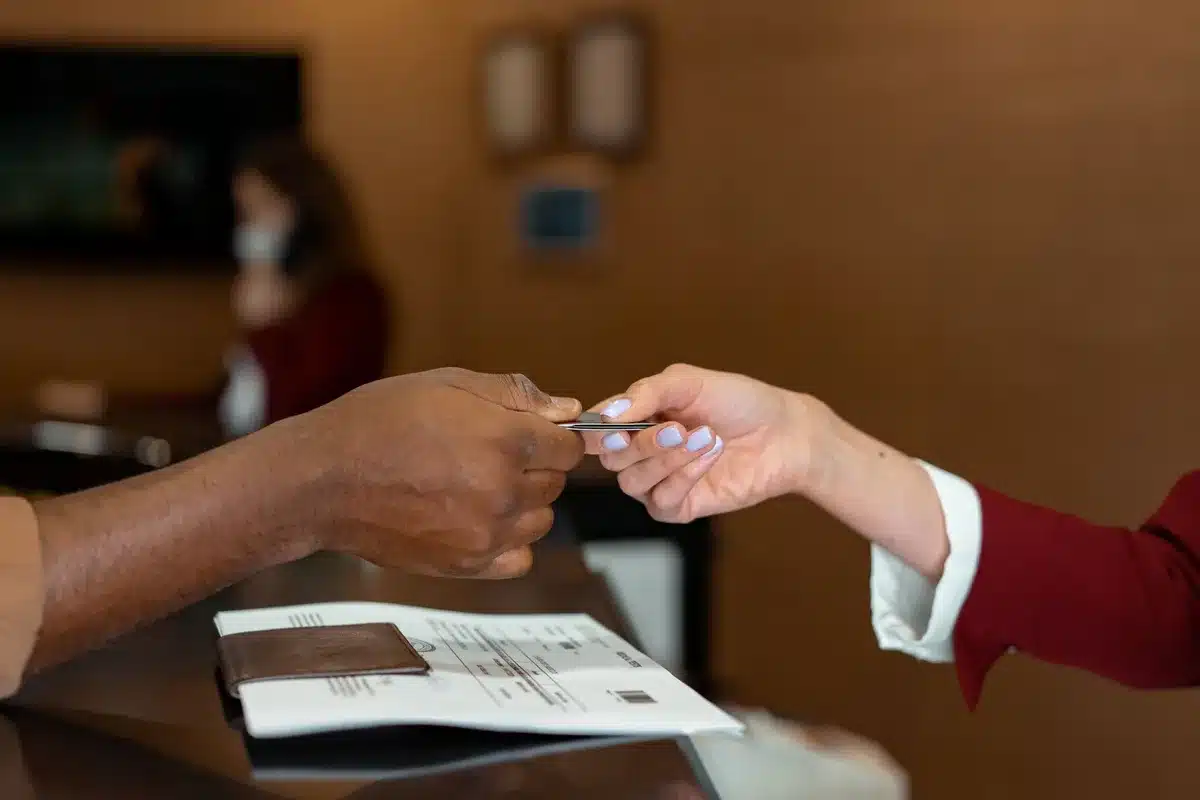 Mains tenant une carte de crédit au-dessus d'un écran d'ordinateur affichant des réservations de vols et d'hôtels