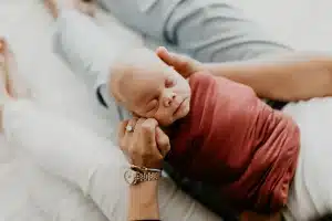 Mains de parent tenant des documents financiers et un certificat de naissance à côté d'un ordinateur portable