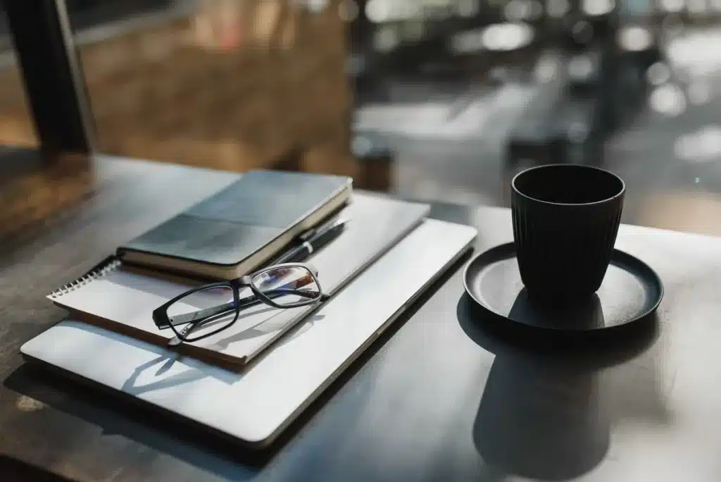 Mains écrivant des notes dans un carnet sur un bureau en lumière douce.