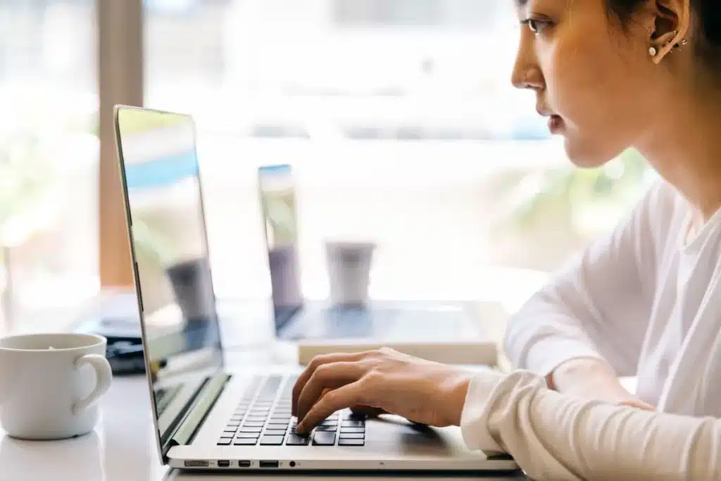 Mains tapant sur un clavier d'ordinateur portable avec un site de recherche d'emploi ouvert à l'écran.