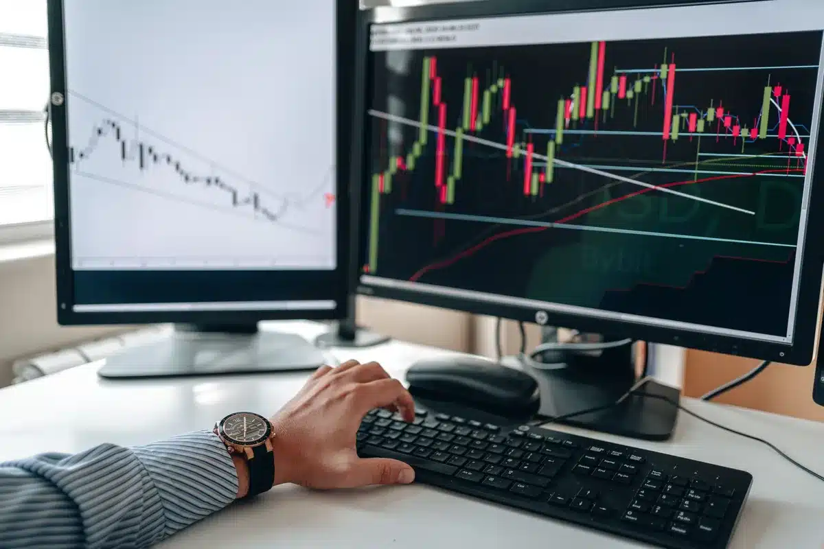 Bureau de trader avec écrans affichant des graphiques boursiers et analyses techniques