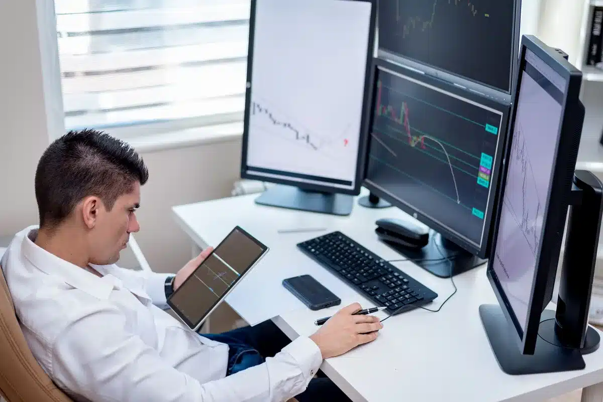 Bureau de trading avec écrans affichant des graphiques de devises et des taux de change en temps réel.