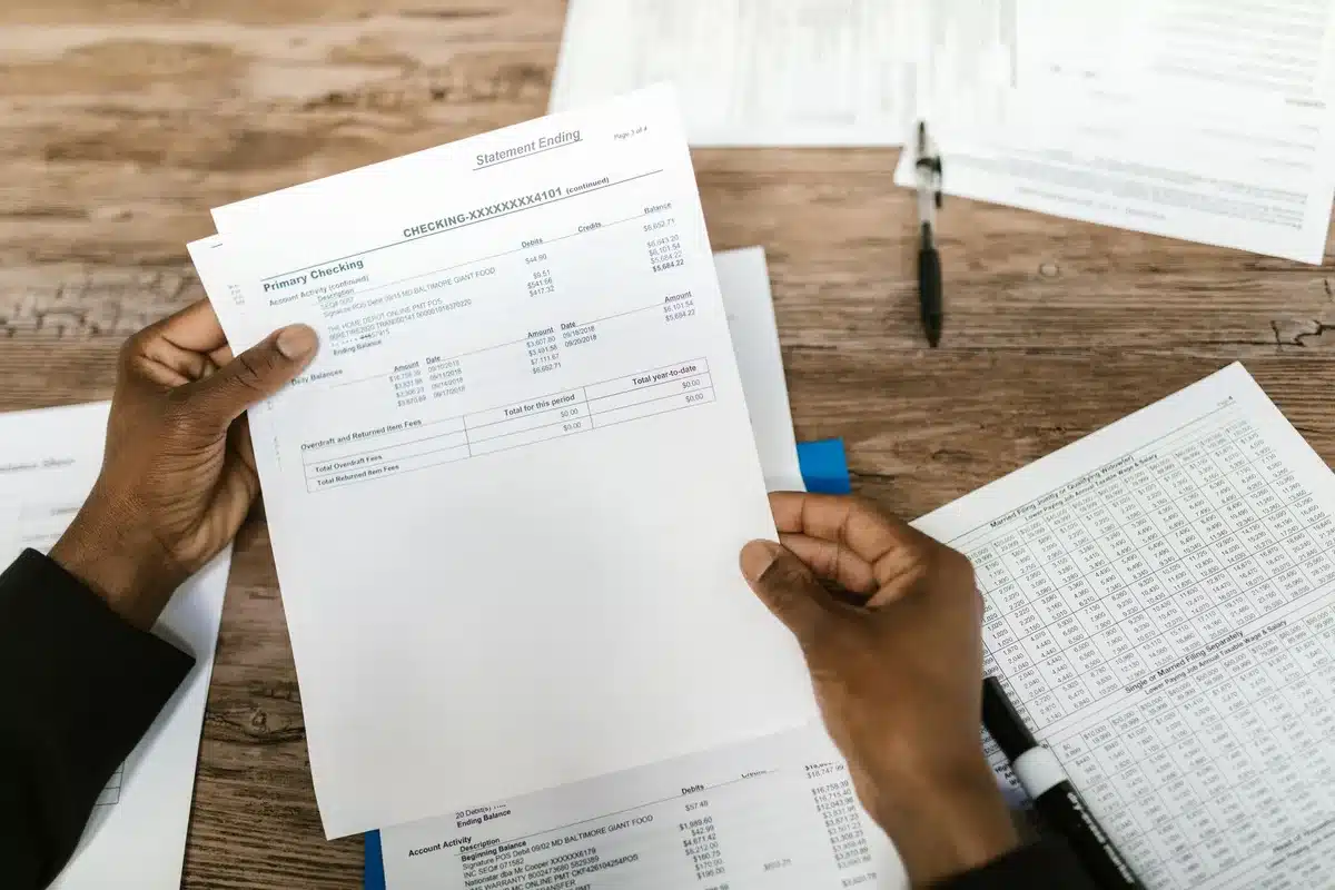 Documents bancaires et conditions contractuelles étalés sur un bureau