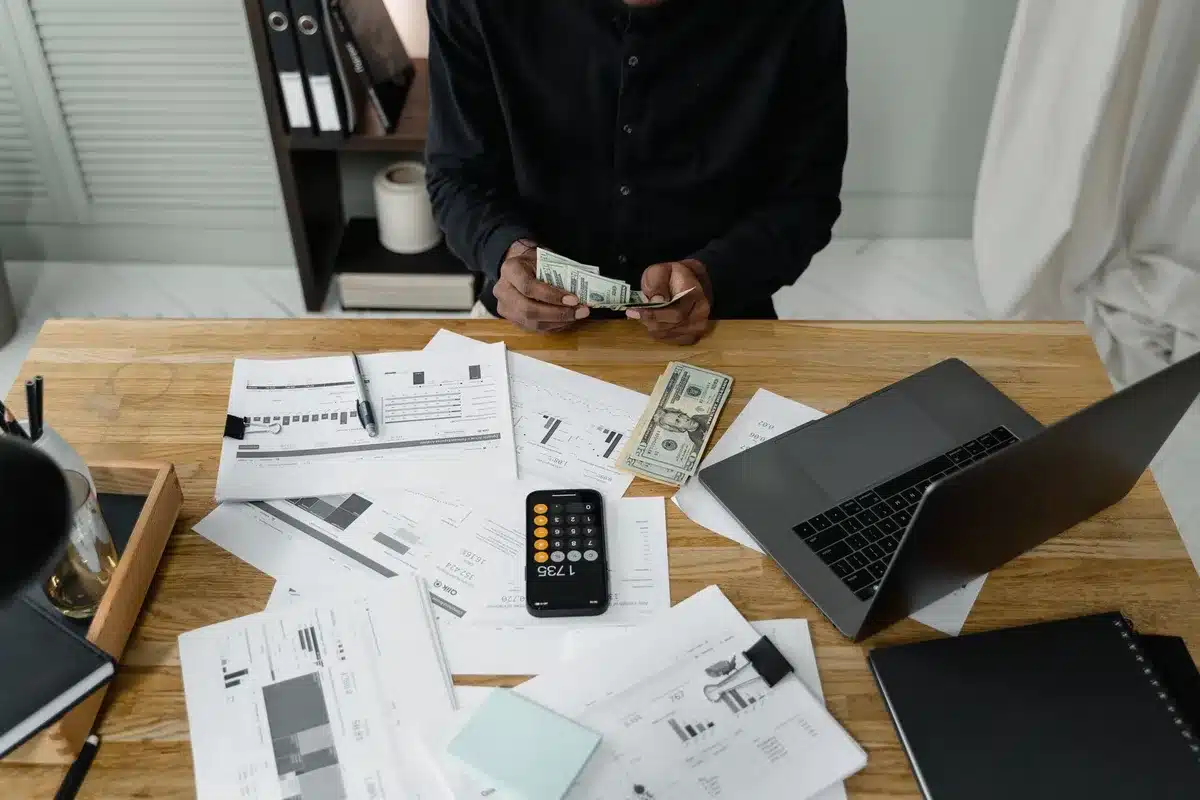 Personne consultant un relevé bancaire sur ordinateur portable avec calculatrice