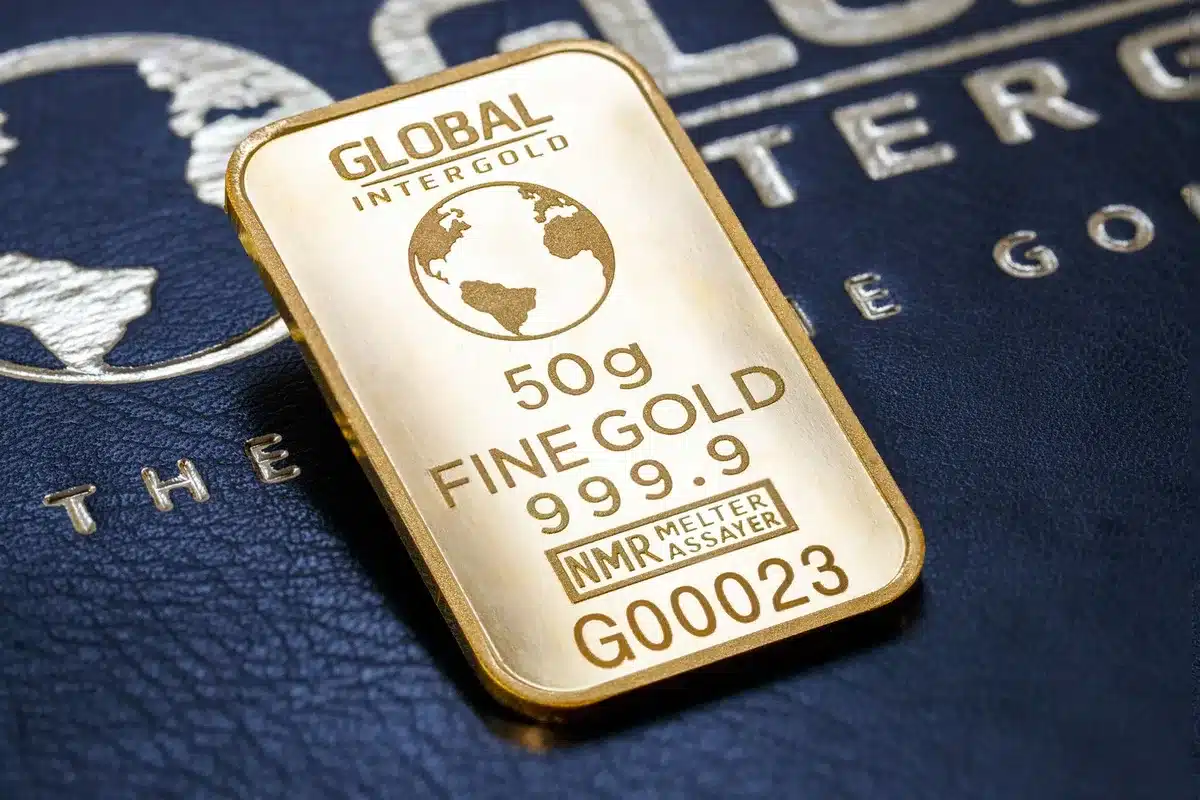 Lingots d'or, grains de blé et échantillons de pétrole brut sur un bureau avec graphiques financiers et devises.