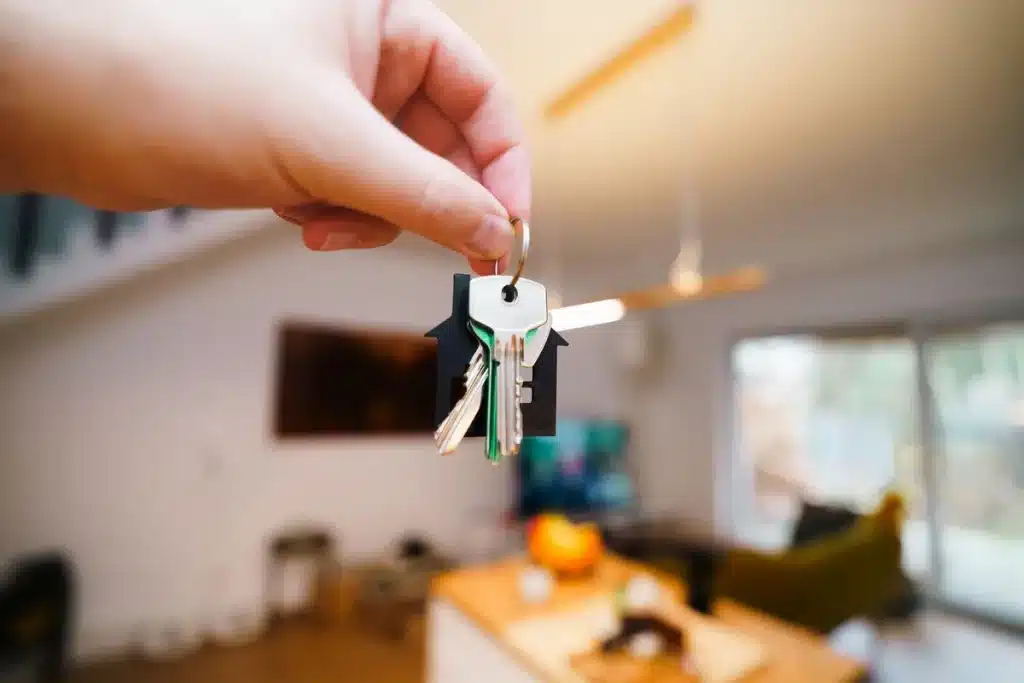 Mains tenant un contrat de location, des clés et des documents administratifs sur un bureau