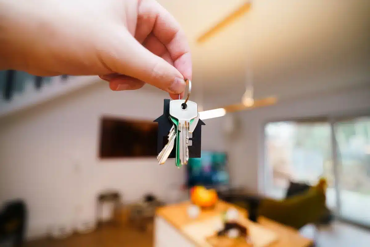 Mains tenant un contrat de location, des clés et des documents administratifs sur un bureau