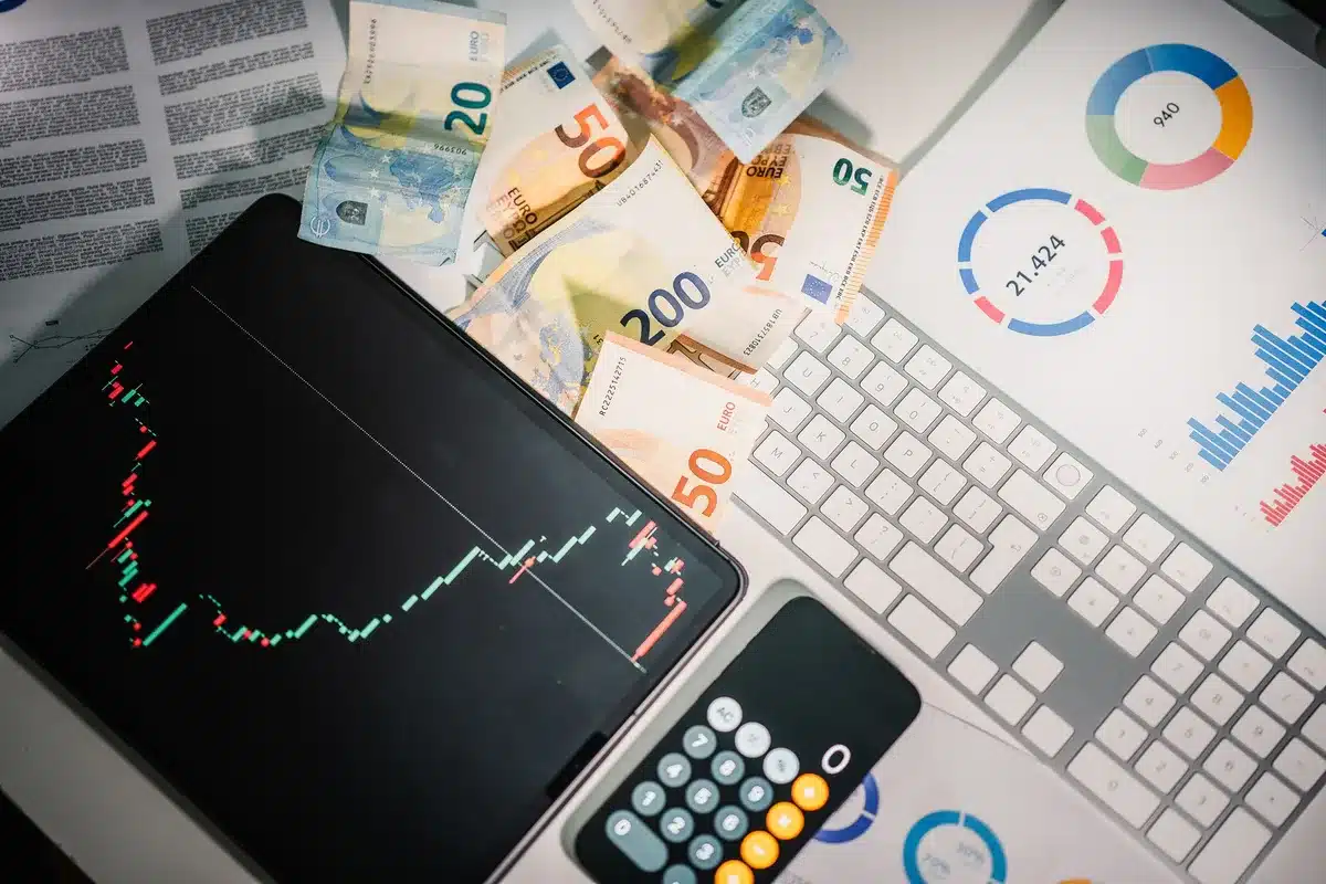 Billets et pièces de yen japonais sur un bureau de trading avec graphiques de marché en arrière-plan