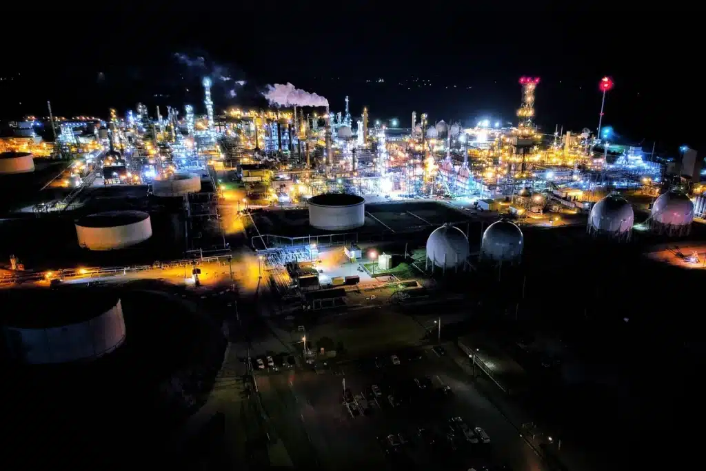 Échantillon de pétrole brut et infrastructure pétrolière en arrière-plan, symbolisant les tensions géopolitiques et l'im
