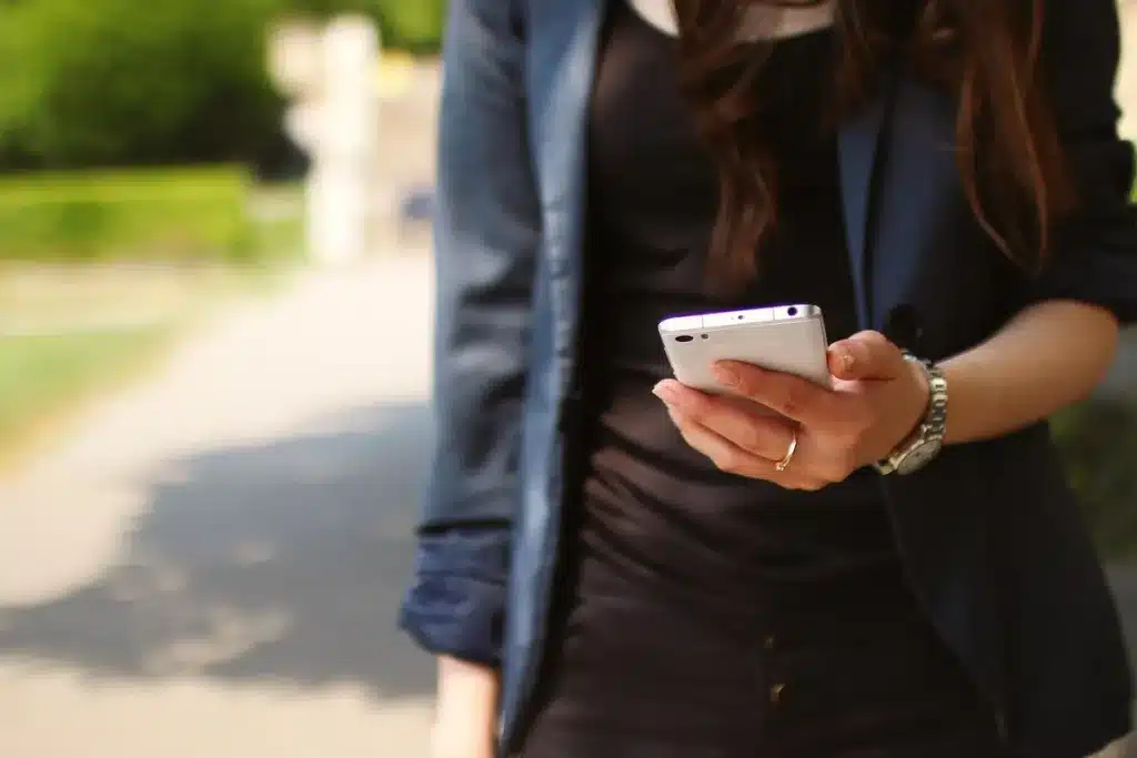Mains anonymes tenant un smartphone au-dessus d'un prospectus d'offre, bureau en plein jour
