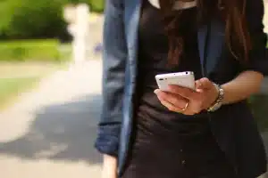 Mains anonymes tenant un smartphone au-dessus d'un prospectus d'offre, bureau en plein jour