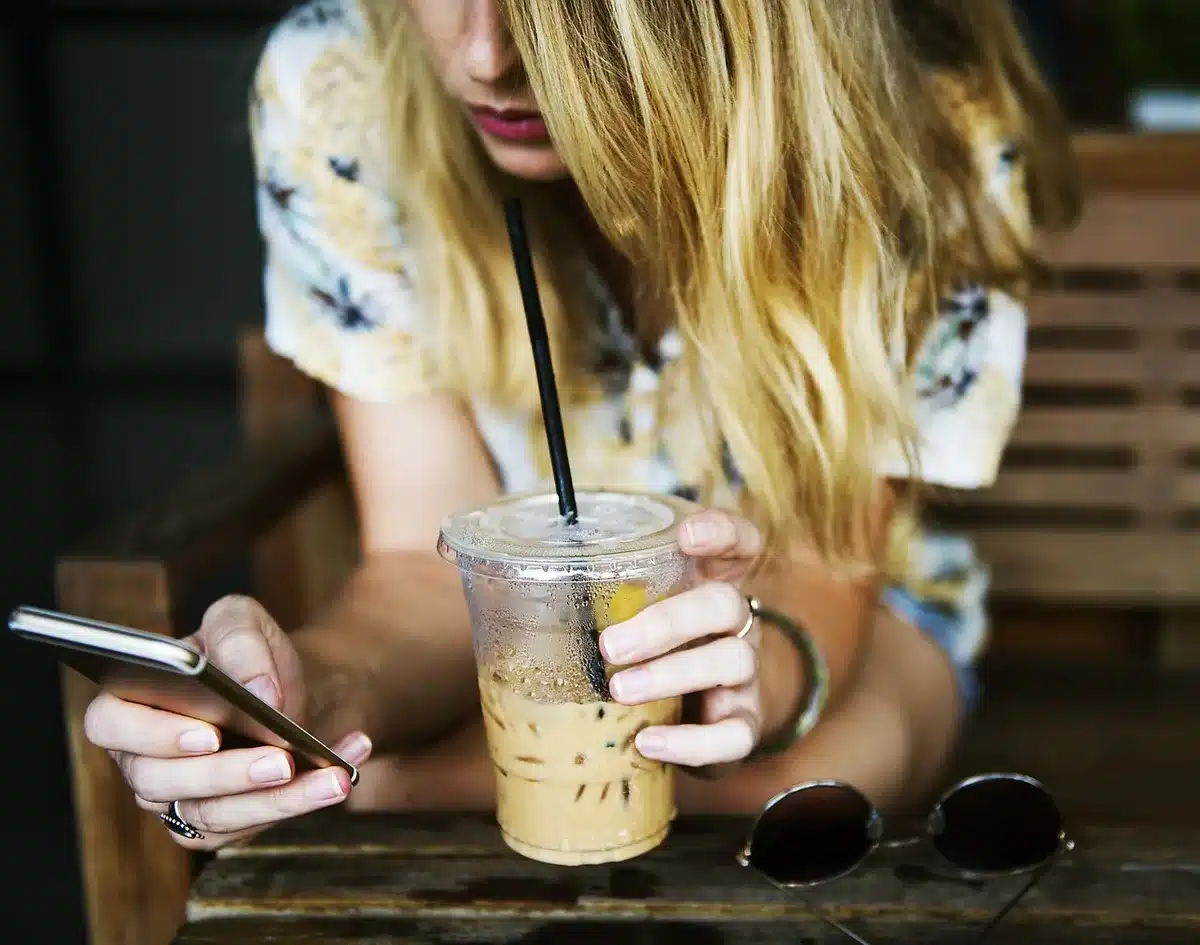 Main posant une carte et téléphone montrant un paiement en cours sur une table de café en journée