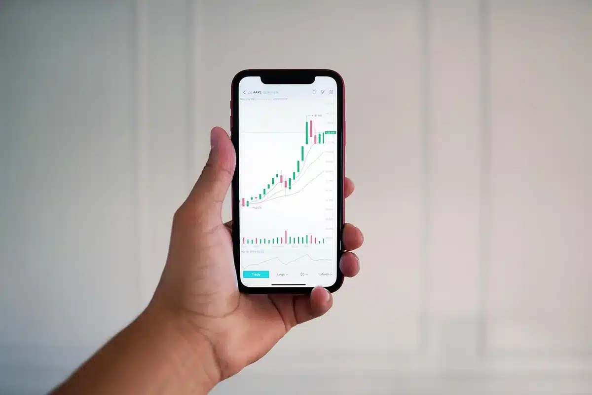 Silhouette d'un trader face à des écrans montrant graphiques boursiers et volumes