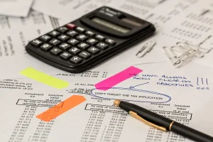 Mains triant des documents bancaires et une calculatrice sur un bureau en plein jour