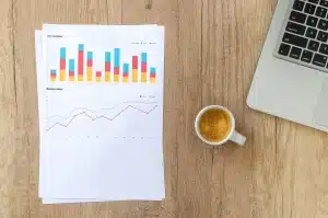 Main pointant des graphiques sectoriels imprimés sur un bureau ensoleillé