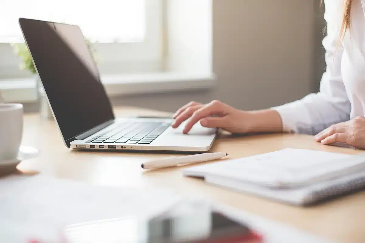 Calculs et estimations financières sur un bureau ensoleillé avec un ordinateur portable