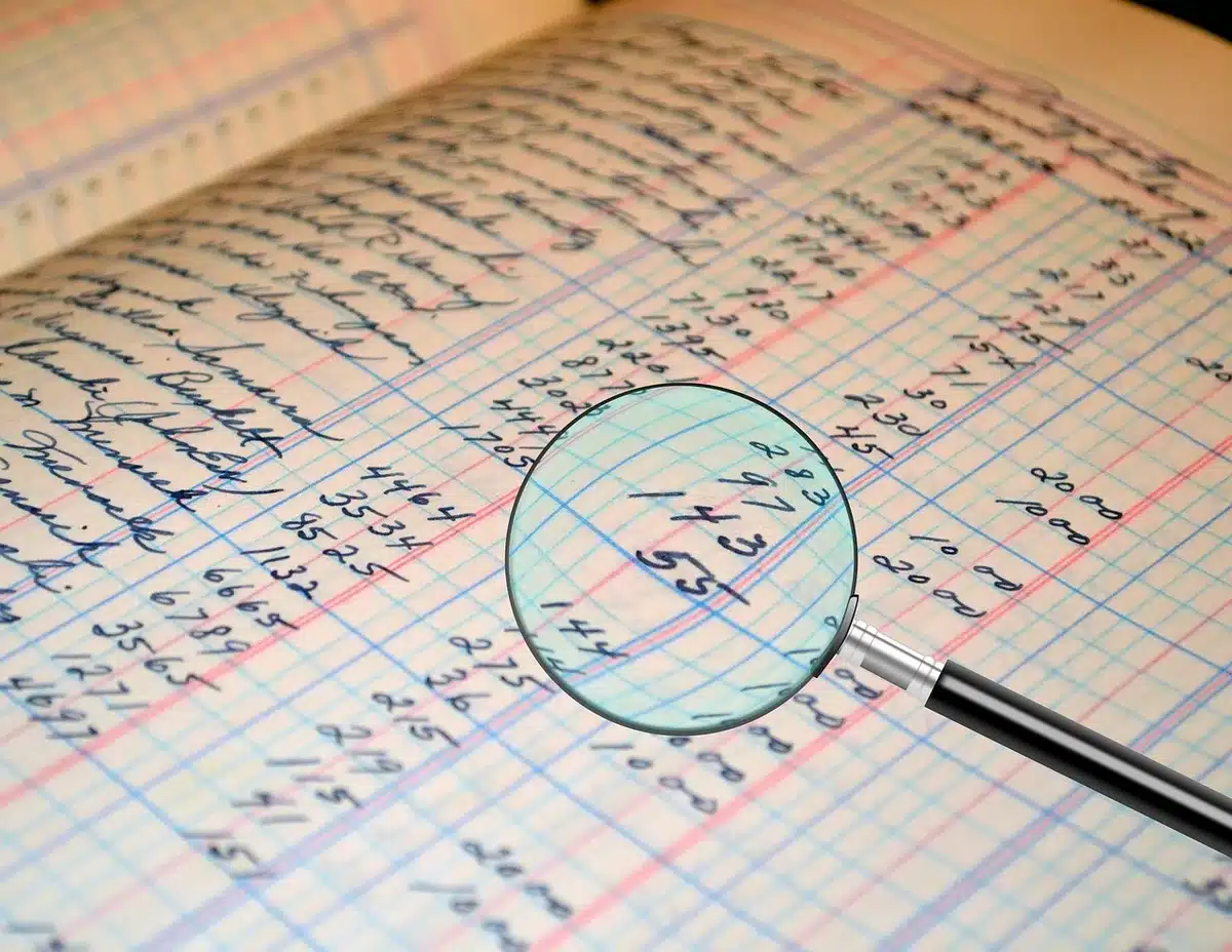 Main sur une calculatrice à côté d'un cahier listant produits financiers