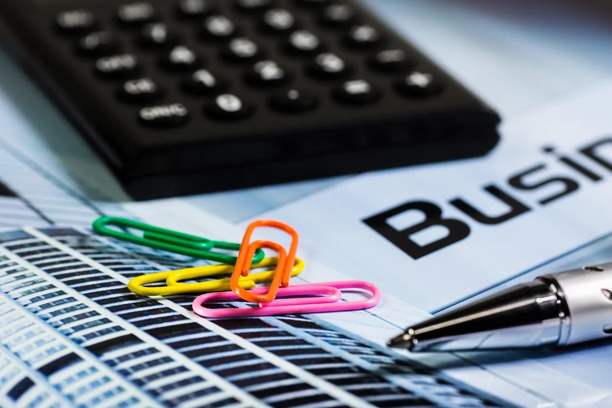 Main feuilletant des documents de retraite et une calculatrice sur une table