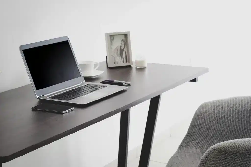 Espace de travail d'un graphiste avec ordinateur, carnets et tasse de café, en plein jour