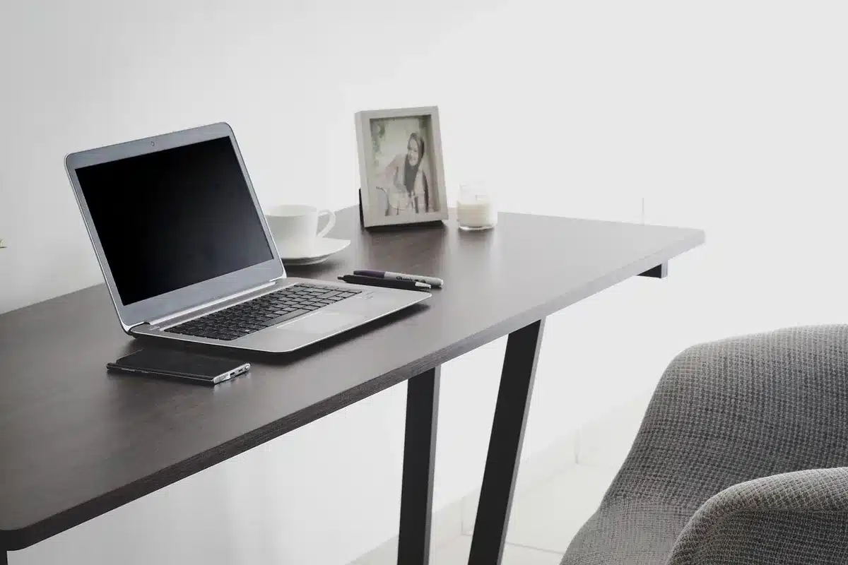 Espace de travail d'un graphiste avec ordinateur, carnets et tasse de café, en plein jour