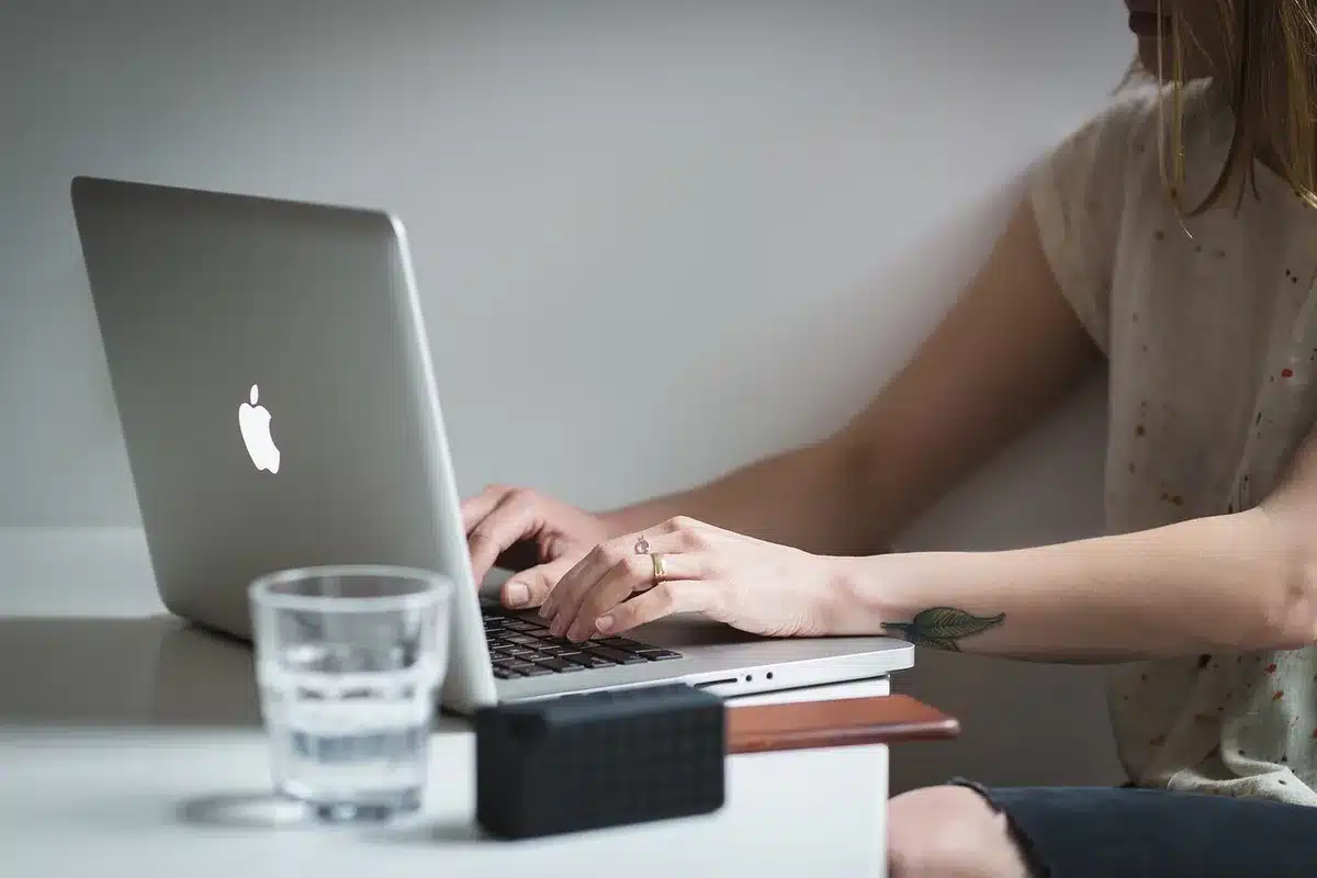 Personne anonymisée tapant sur un ordinateur portable en révisant des documents médicaux