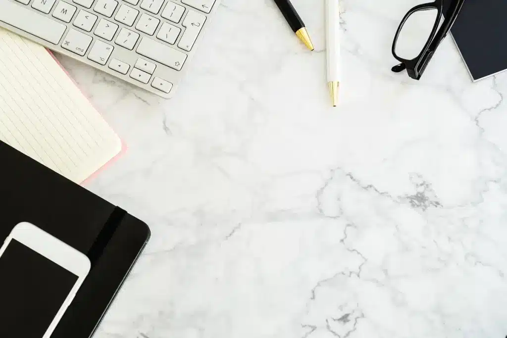 Bureau baigné de lumière avec relevés, calculatrice et mains organisant notes