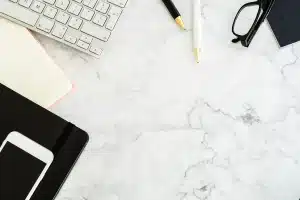 Bureau baigné de lumière avec relevés, calculatrice et mains organisant notes