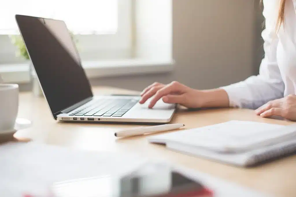 Bureau bancaire en journée avec documents, ordinateur portable et mains anonymes examinant un graphique