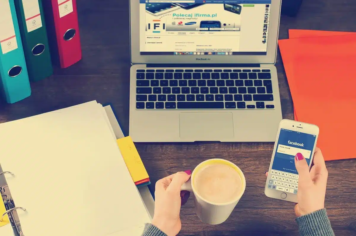 Bureau lumineux avec mains feuilletant un rapport sectoriel près d'un ordinateur et une tasse de café