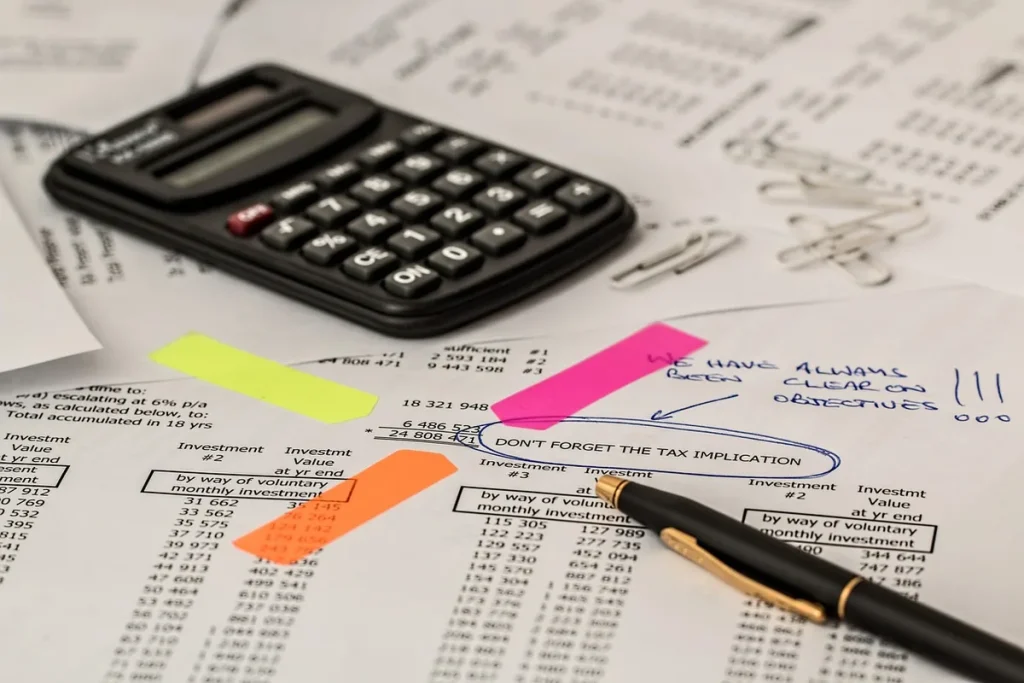 Mains sur des documents bancaires et une calculatrice sur un bureau en plein jour