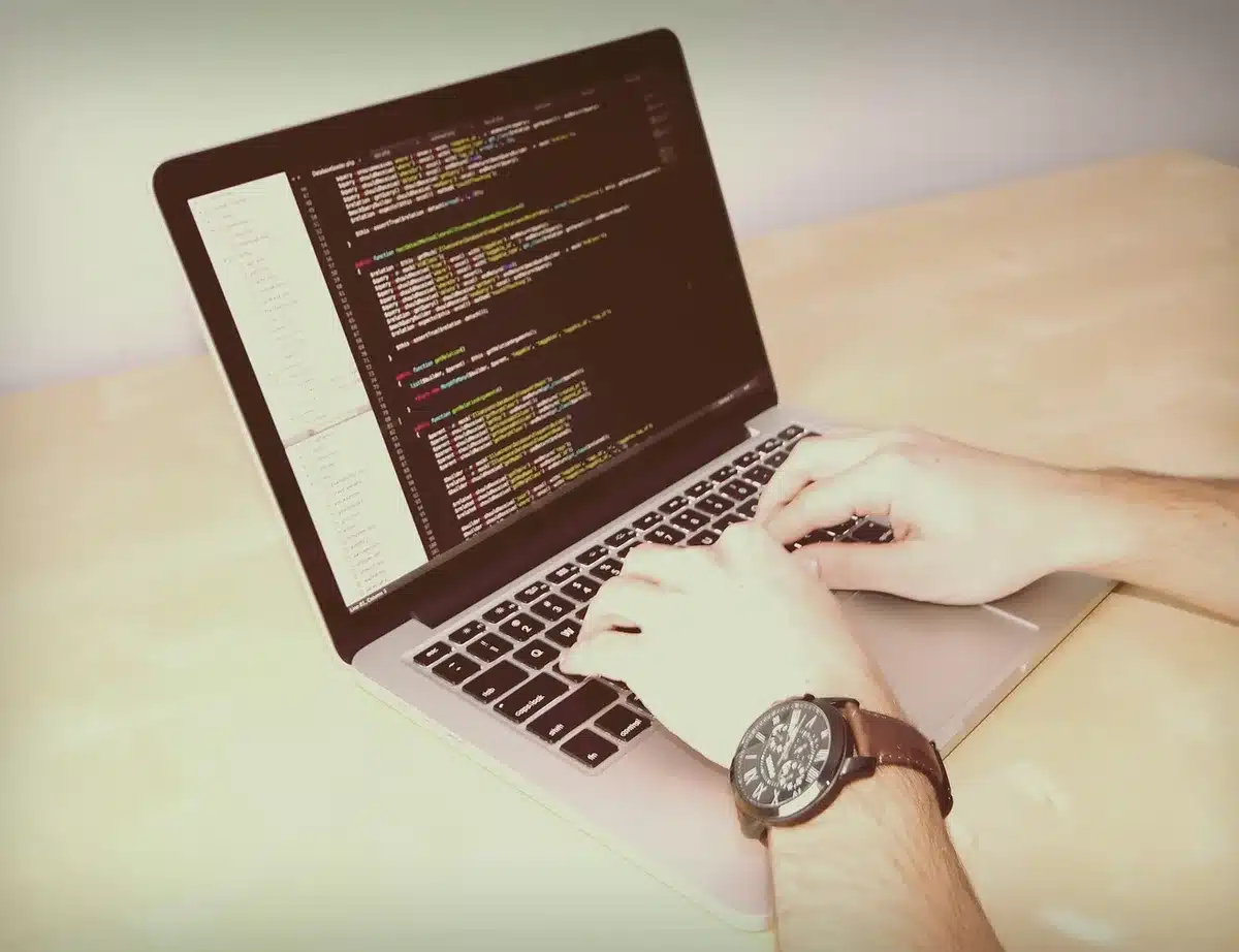 Bureau en journée avec ordinateur portable affichant du code et notes techniques