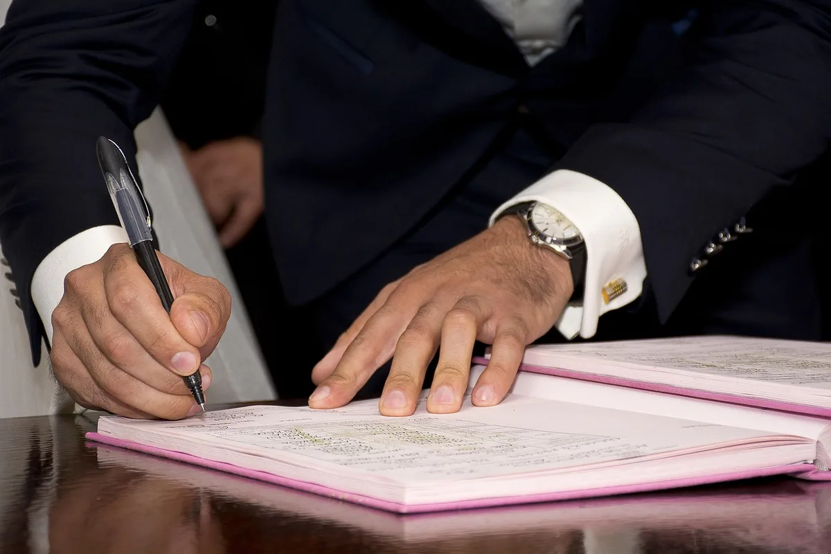 Contrat et papiers posés sur une table avec stylo et lunettes en lumière du jour