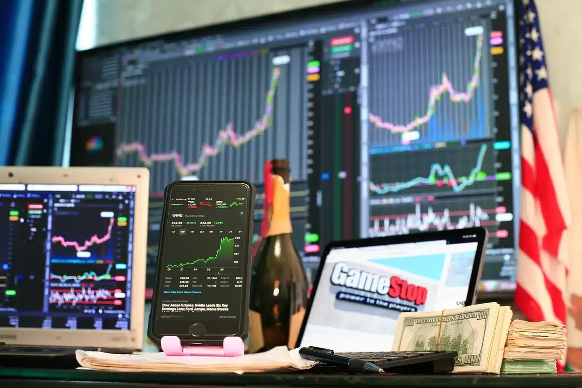 Écran et documents montrant la baisse du Nasdaq et chiffres boursiers
