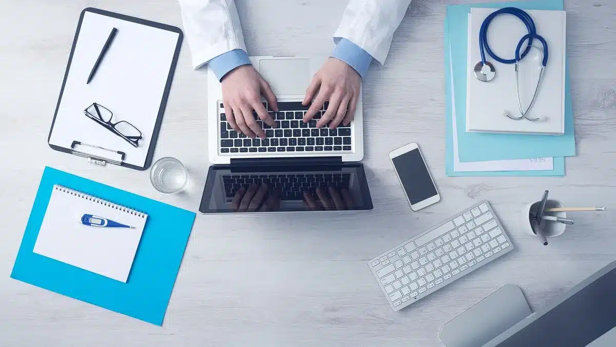 Bureau en plein jour avec ordinateur portable et notes montrant des schémas de réseau