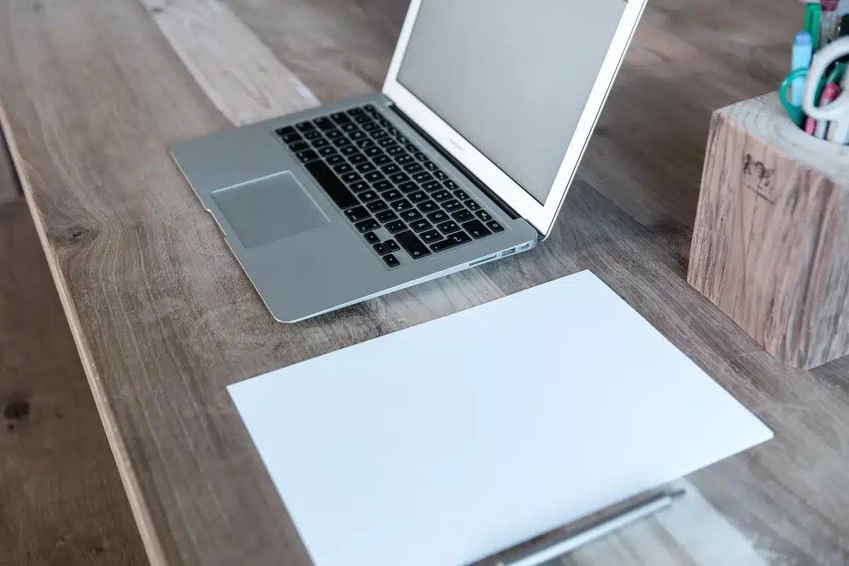 Personne anonyme travaillant sur un ordinateur portable avec graphique financier et checklist sur un bureau en plein jou