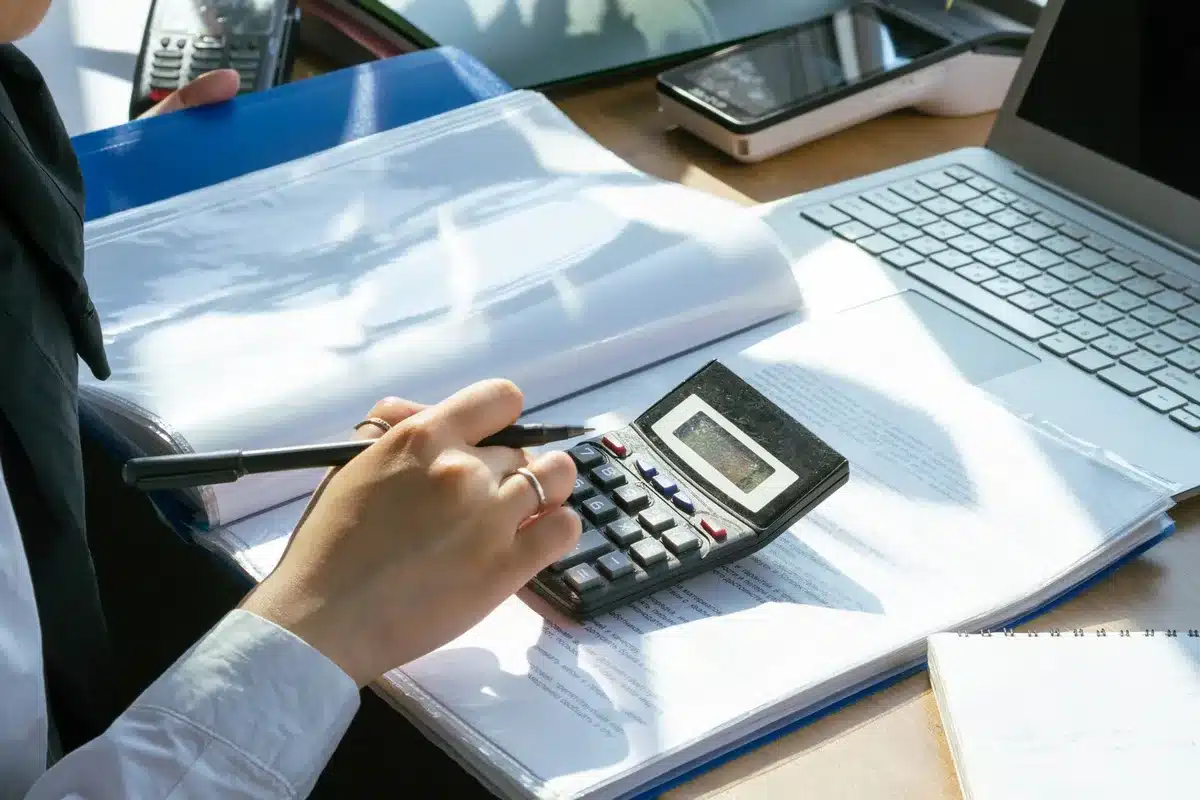 Dossier financier et calculatrice sur un bureau éclairé par la lumière du jour